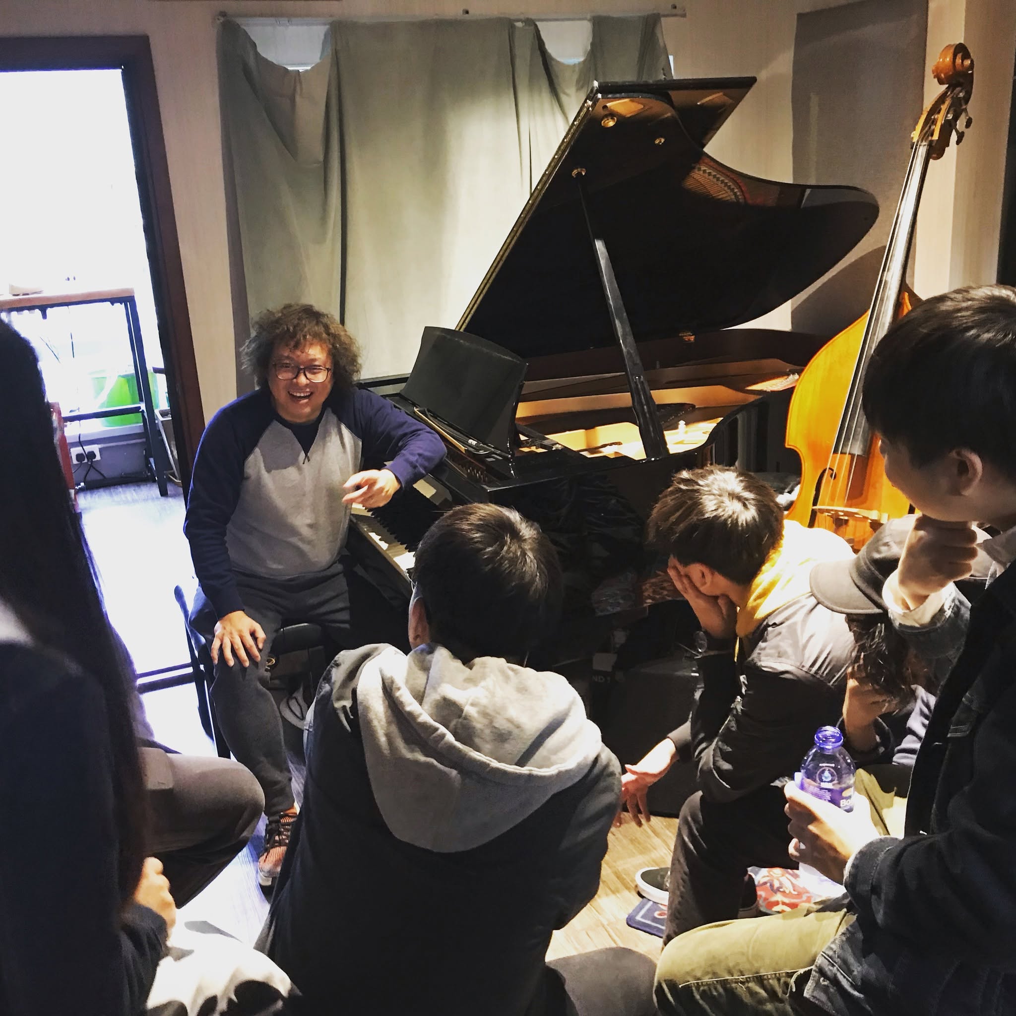 Ryui leading a group music workshop beside a grand piano